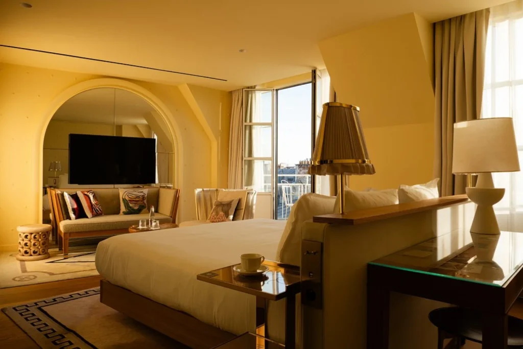 Sophisticated guest room with warm interiors, elegant furnishings and large windows overlooking Paris at 9Confidentiel, Paris, France