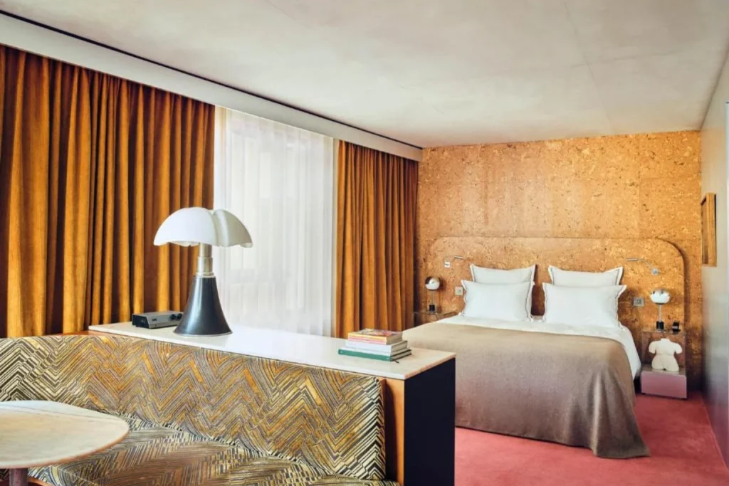 Modern guest room with warm orange tones and contemporary furnishings at Bus Palladium in Paris