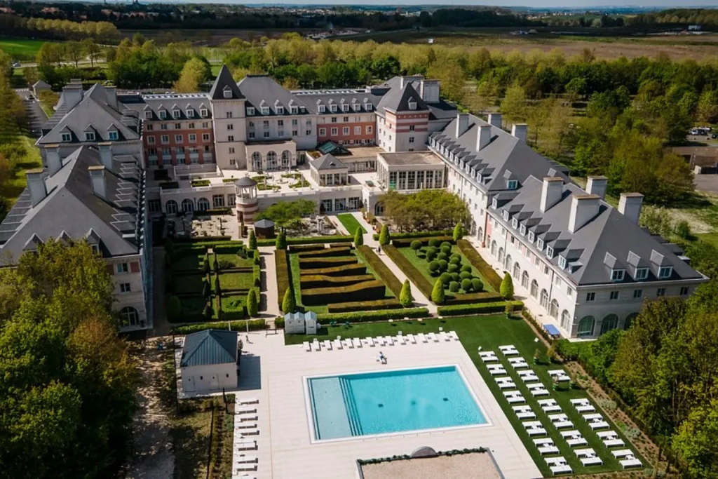 Aerial view of the outdoor swimming pool and landscaped formal gardens at Dream Castle Hotel near Disneyland Paris.