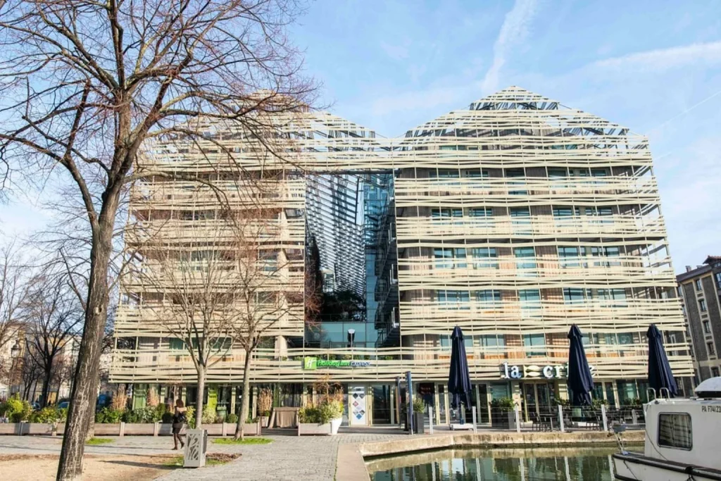 Exterior with modern glass architecture and a canal in front at Holiday Inn Express Paris