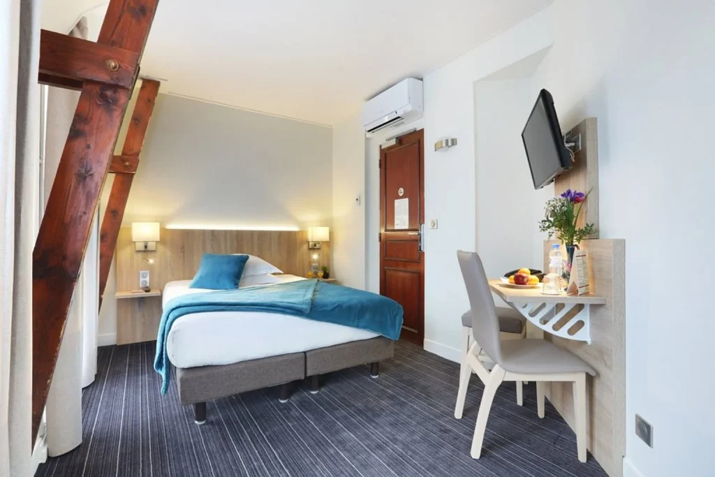 Bright contemporary guest room with a double bed, blue accents and a compact work area at Hotel Beaugrenelle Tour Eiffel in Paris.