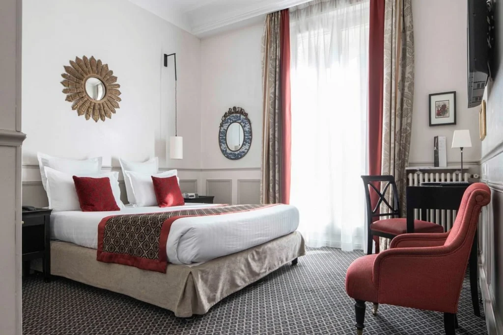 Elegant bedroom with red accents, decorative mirrors and classic Parisian furnishings at Hôtel Bradford Elysées – Astotel Paris.