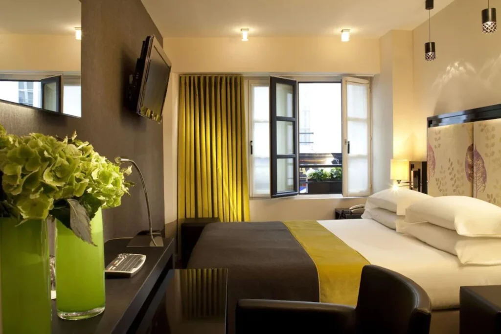Stylish boutique room with a comfortable double bed, vibrant green details and natural light at Hôtel Caron le Marais, Paris, France