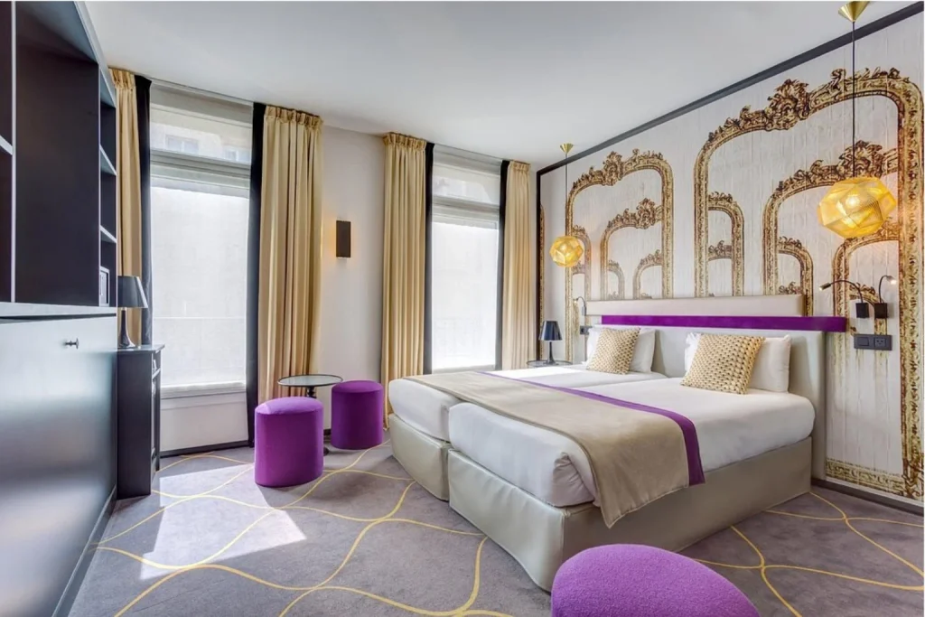 Stylish guest room with twin beds, purple accents and ornate decorative wall panels at Hôtel Daline Eiffel in Paris.