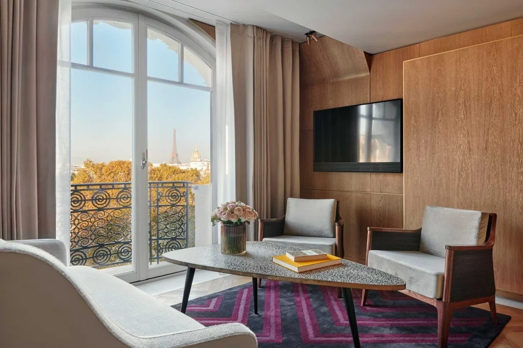 Elegant luxury suite living room with wood-paneled walls, contemporary seating and windows overlooking the Eiffel Tower at Hôtel Lutetia, Paris
