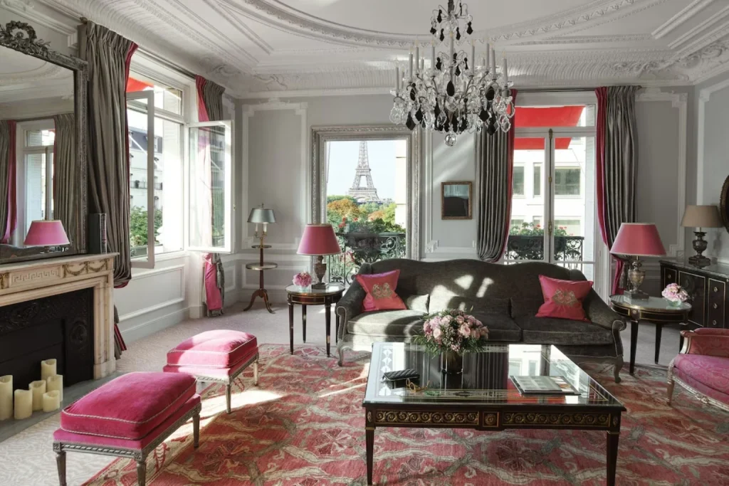 Opulent Parisian suite with pink accents, ornate detailing and a beautifully framed view of the Eiffel Tower at Hôtel Plaza Athénée in Paris.
