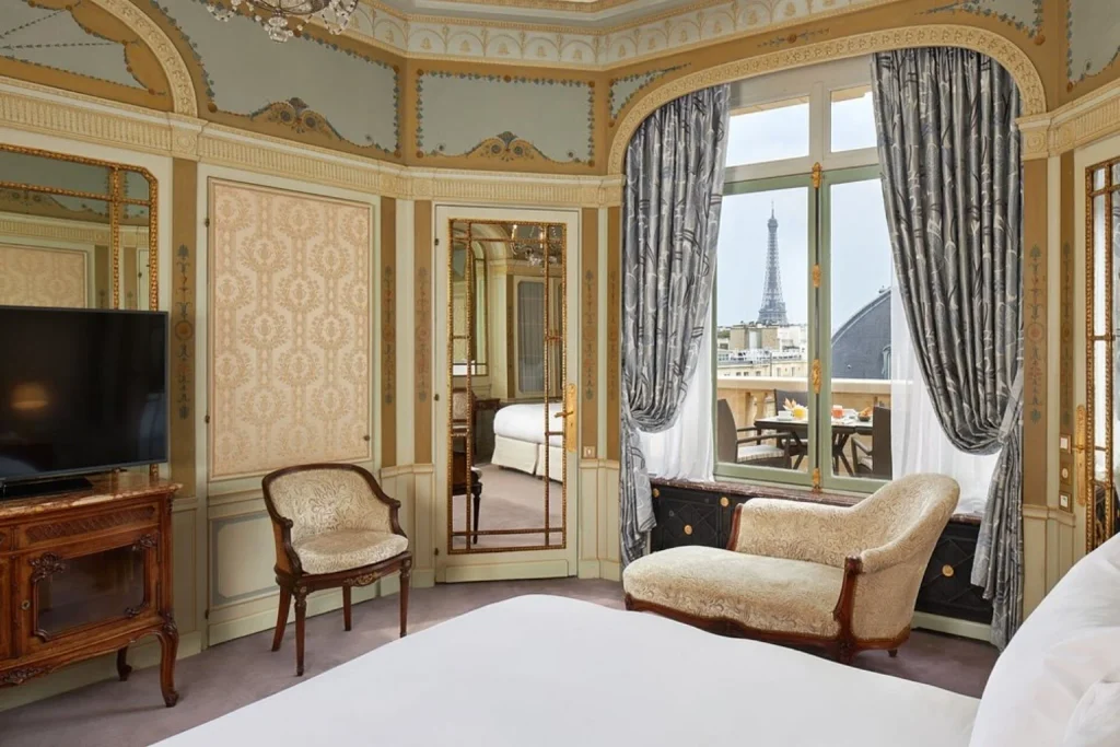 Ornate Parisian-style guest room with period furnishings and a direct view of the Eiffel Tower at Hôtel Raphael Paris.