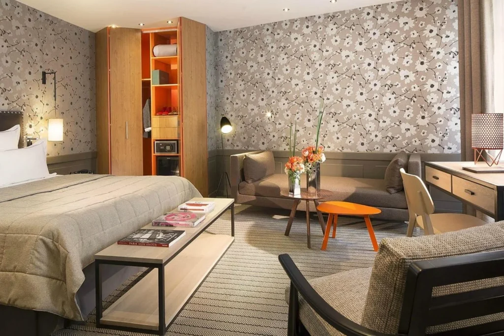Stylish guest room with floral wallpaper, a comfortable sitting area and contemporary furnishings at Hôtel Signature Saint Germain des Près Paris.