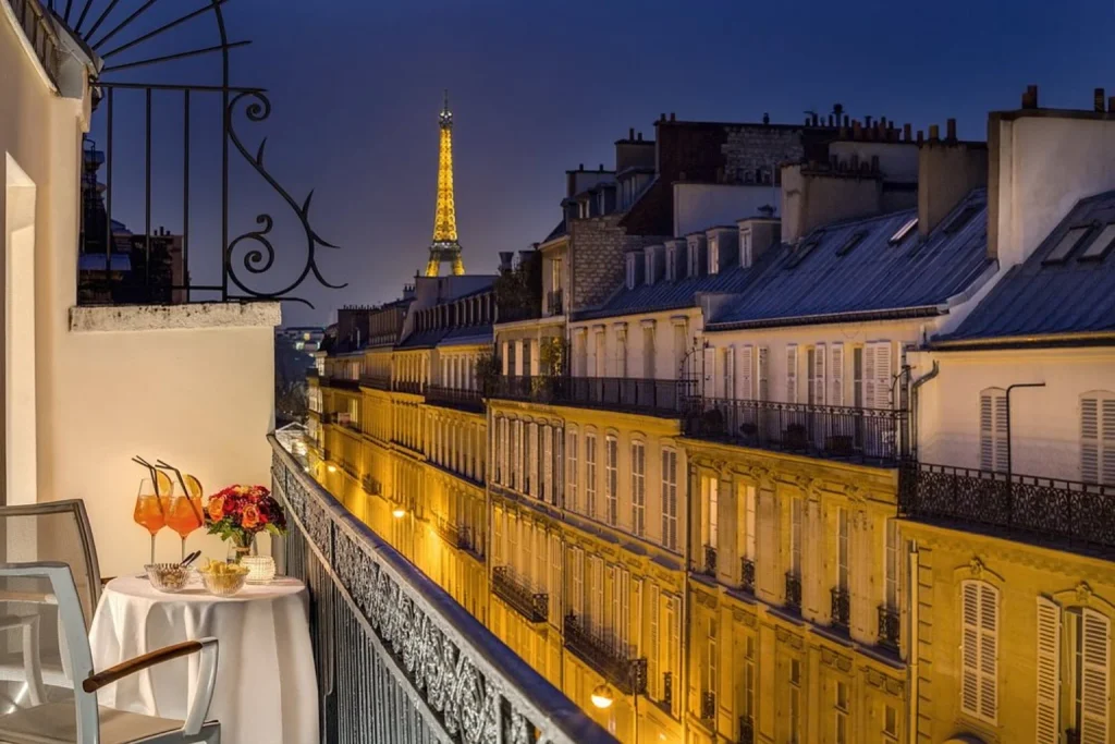 Romantic private balcony with cocktails, flowers and illuminated Eiffel Tower views at night at Hôtel Splendide Royal Paris