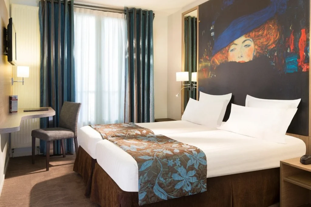 Bright boutique hotel room featuring comfortable beds, rich blue accents and a distinctive artistic mural at Hotel Turenne Le Marais, Paris, France