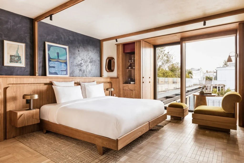 Modern luxury bedroom with warm wood interiors, contemporary artwork and floor-to-ceiling windows at La Fondation, Paris