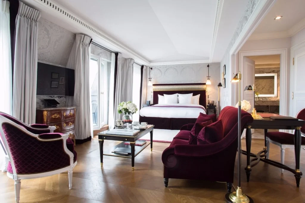 Elegant luxury suite with burgundy furnishings and classic Parisian décor at La Réserve Paris Hotel and Spa