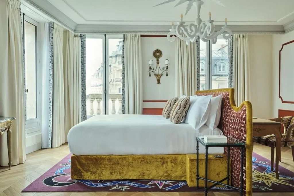 Elegant guest room with statement velvet bed and classic Parisian details at L’Aventure in Paris