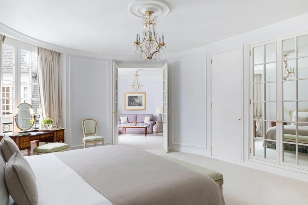 Elegant luxury hotel suite with king-size bed, crystal chandeliers, classic French décor and separate sitting room at Le Bristol Paris