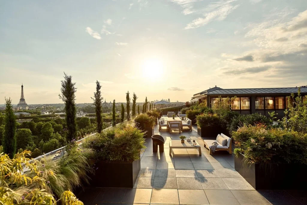 Stunning rooftop terrace featuring stylish lounge furniture, landscaped gardens and breathtaking sunset views of the Eiffel Tower and Paris skyline at Le Meurice in Paris.