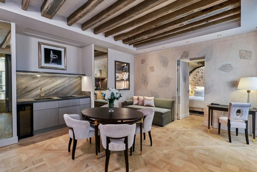 Luxury suite with dining and living area, exposed wooden beams and elegant décor at Maison Barrière Vendôme in Paris