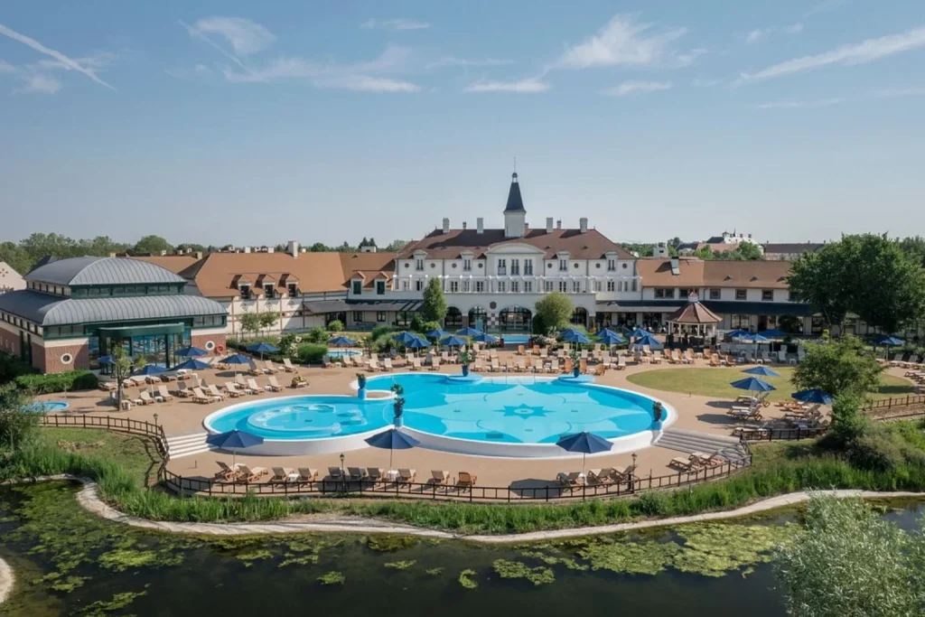Large outdoor swimming pool surrounded by resort buildings and gardens at Marriott’s Village d’Île-de-France near Disneyland Paris.