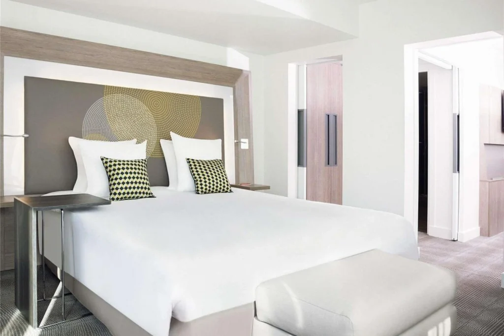 Modern hotel bedroom with a large double bed, white bedding, geometric cushions and contemporary furnishings at Novotel Paris Les Halles