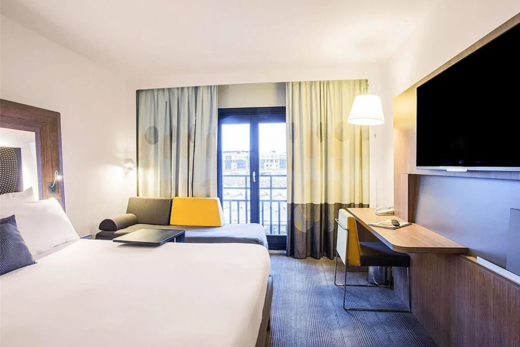 Modern guest room with double bed, seating area and desk at Novotel Paris Les Halles