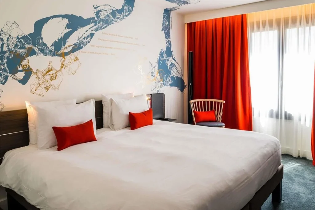 Modern guest room with a large bed, artistic wall design and red accents at Novotel Paris Les Halles