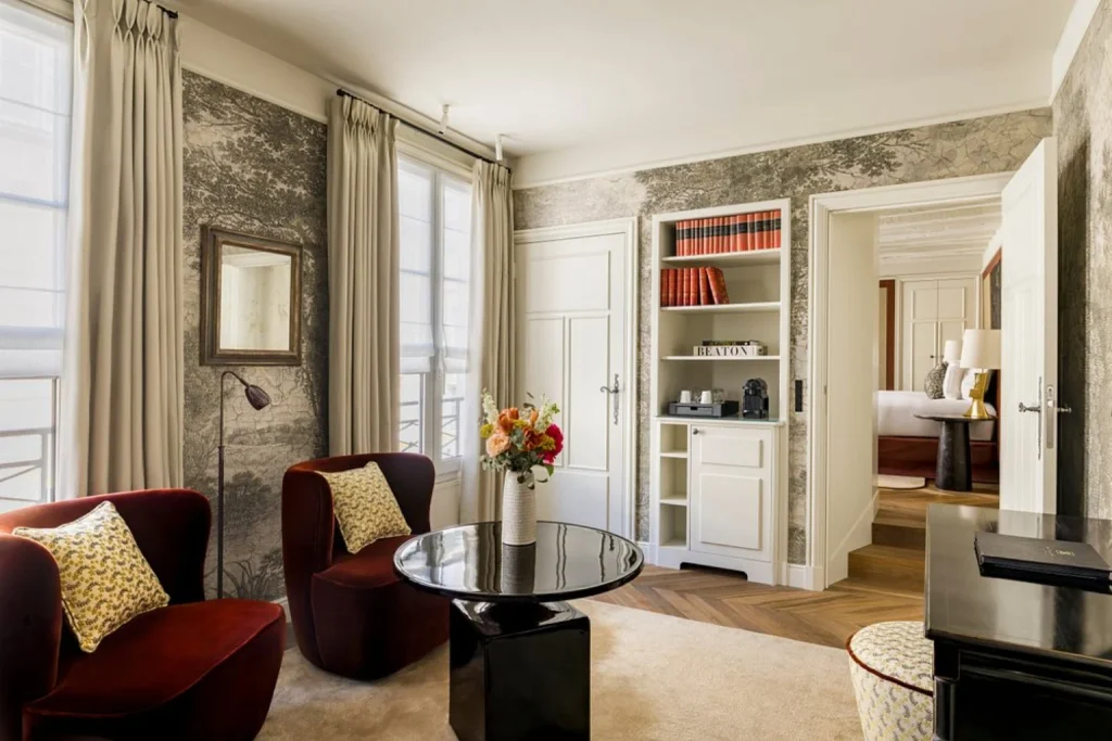 Elegant luxury suite with velvet armchairs, floral wallpaper and classic French interiors at Pavillon de la Reine & Spa, Paris, France