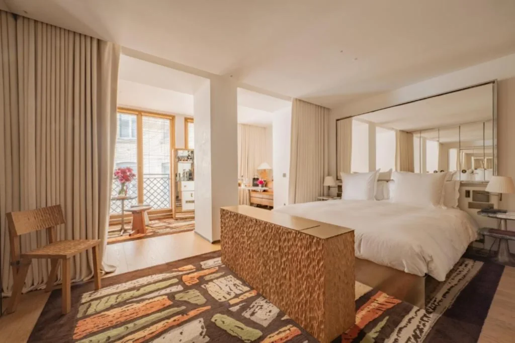 Spacious luxury bedroom with a king bed, contemporary furnishings, large mirror and natural light at SAX Paris, LXR Hotels & Resorts