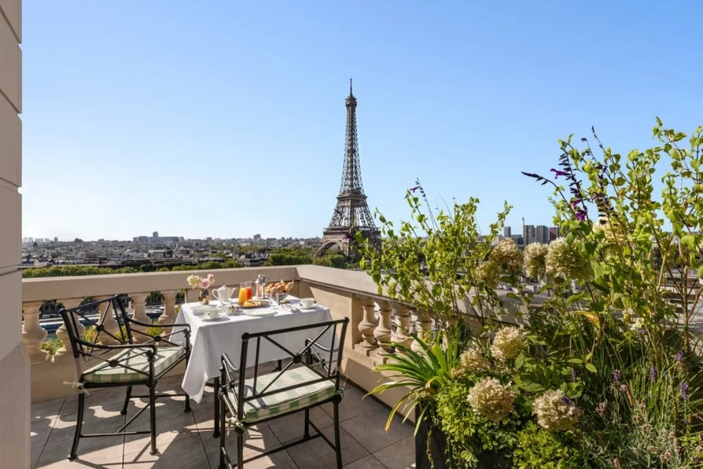 Elegant private terrace with an outdoor breakfast setting, lush greenery and a spectacular direct view of the Eiffel Tower at Shangri-La Paris.
