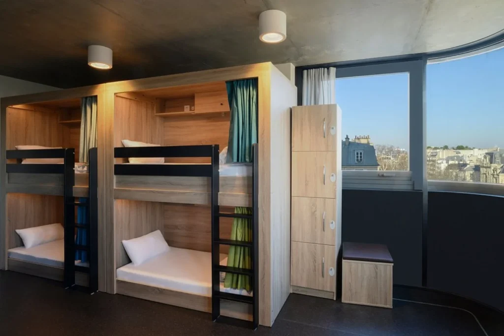 Modern hostel dorm room with wooden bunk beds, lockers and city views at The People Paris Marais