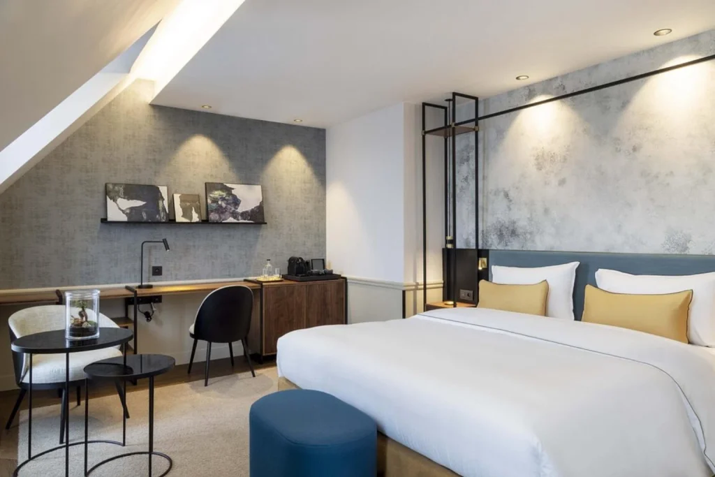 Contemporary bedroom with a king-size bed, work desk and comfortable sitting area at Victoria Palace Hotel Paris.